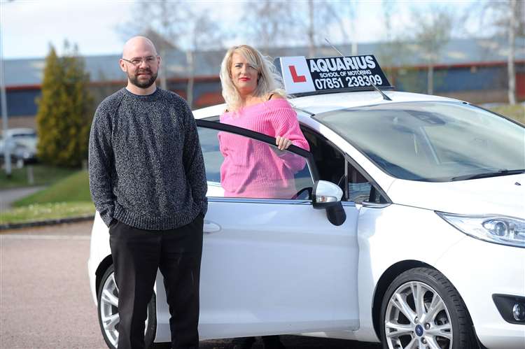Hypnotherapist and driving instructor stand by liveried training car Hypnotherapist Benjamin Ryan with Tarah Macintyre of Aquarius Driving School
